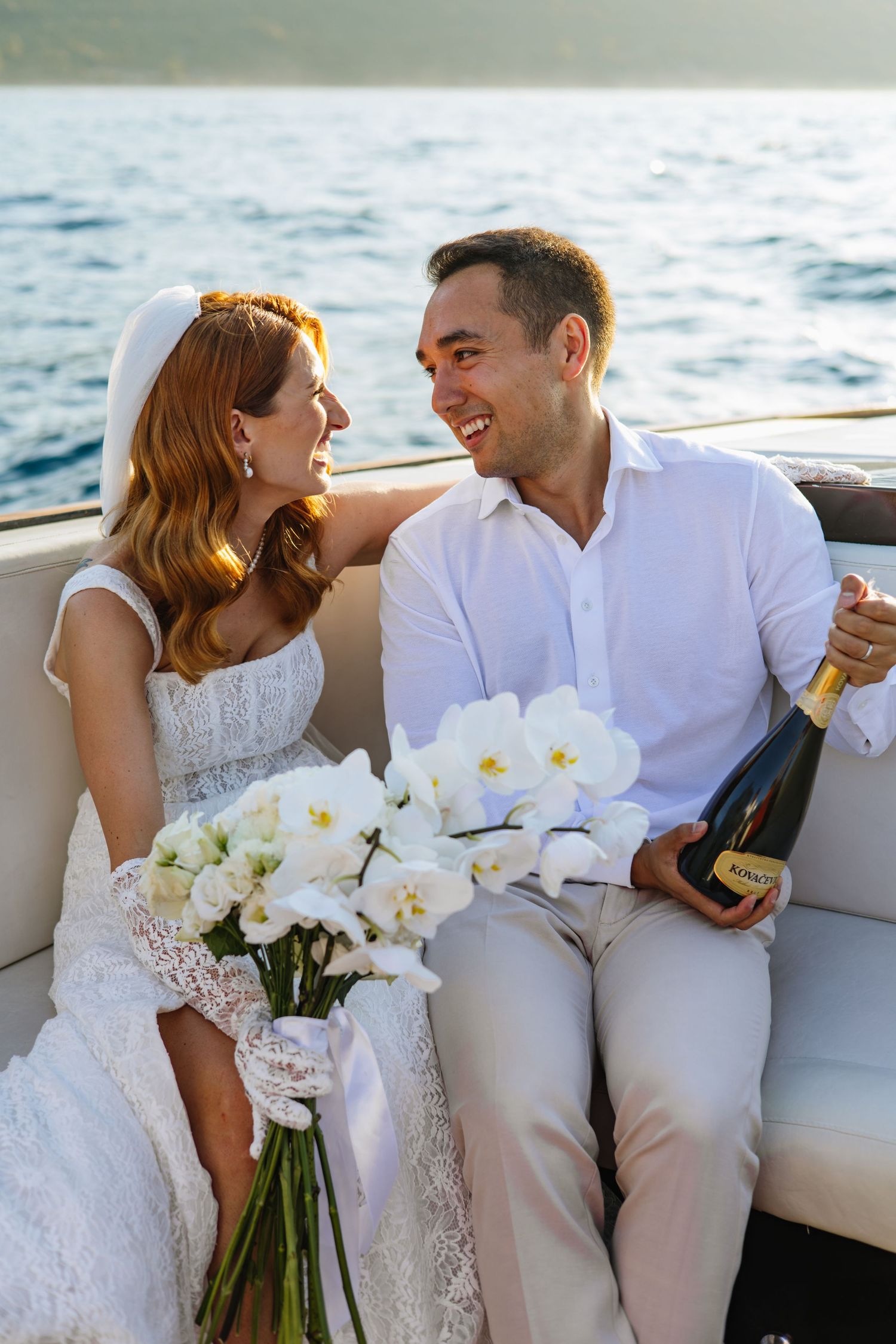 A couple celebrates with champagne and white orchids on a boat during a romantic sunset cruise.