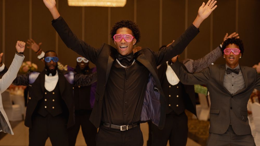 Guests and performers with arms raised joyfully dance and celebrate together at an indoor event.