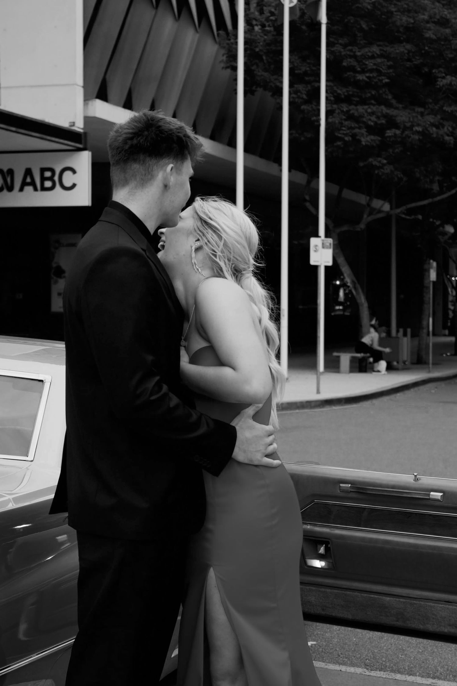 Romantic black and white moment between couple by parked cars.