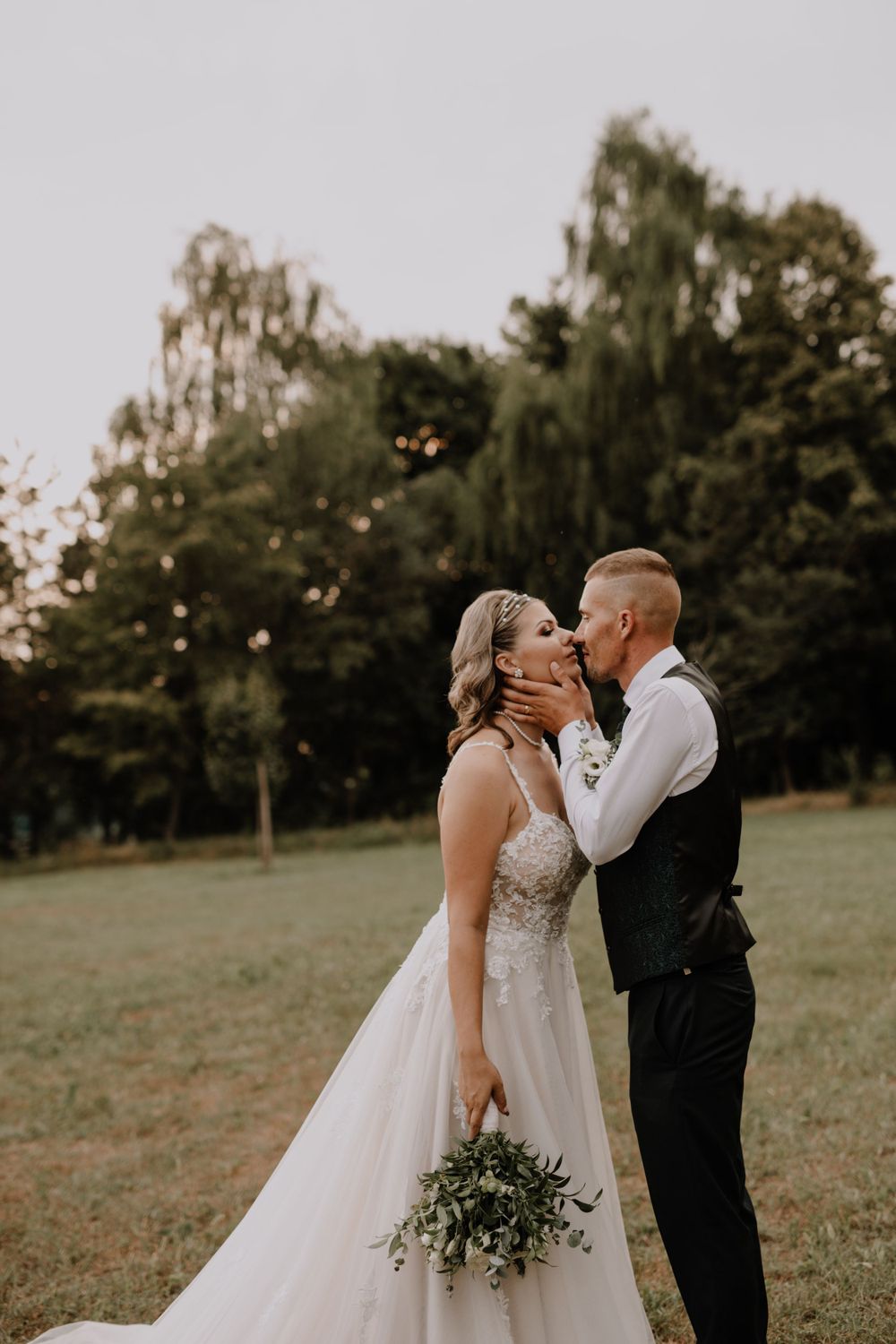 Romantic wedding portrait in outdoor field with willow trees.