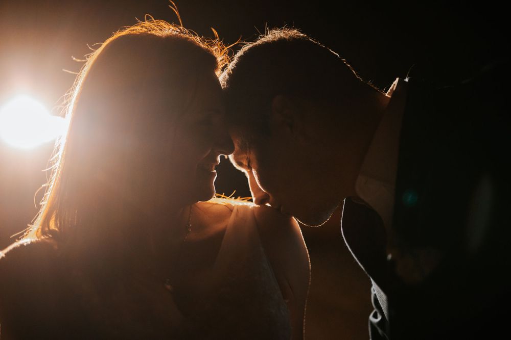 Silhouette of couple's intimate moment backlit with golden light.