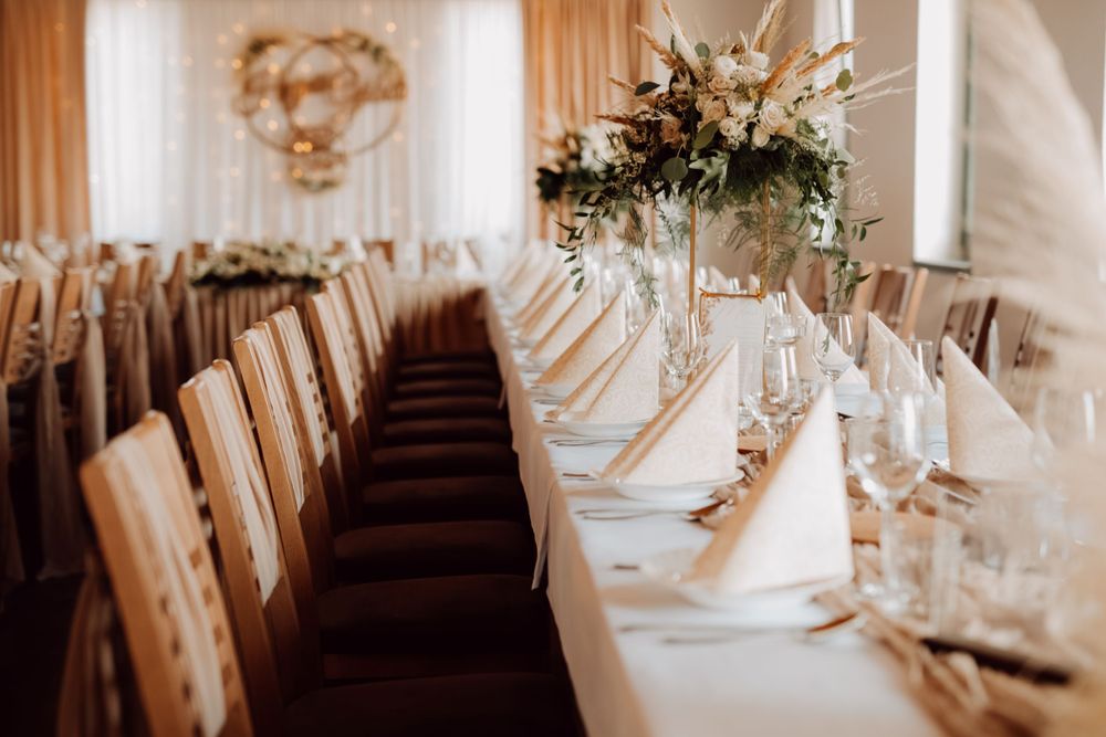 Long banquet tables set with elegant place settings and napkins for a wedding reception.