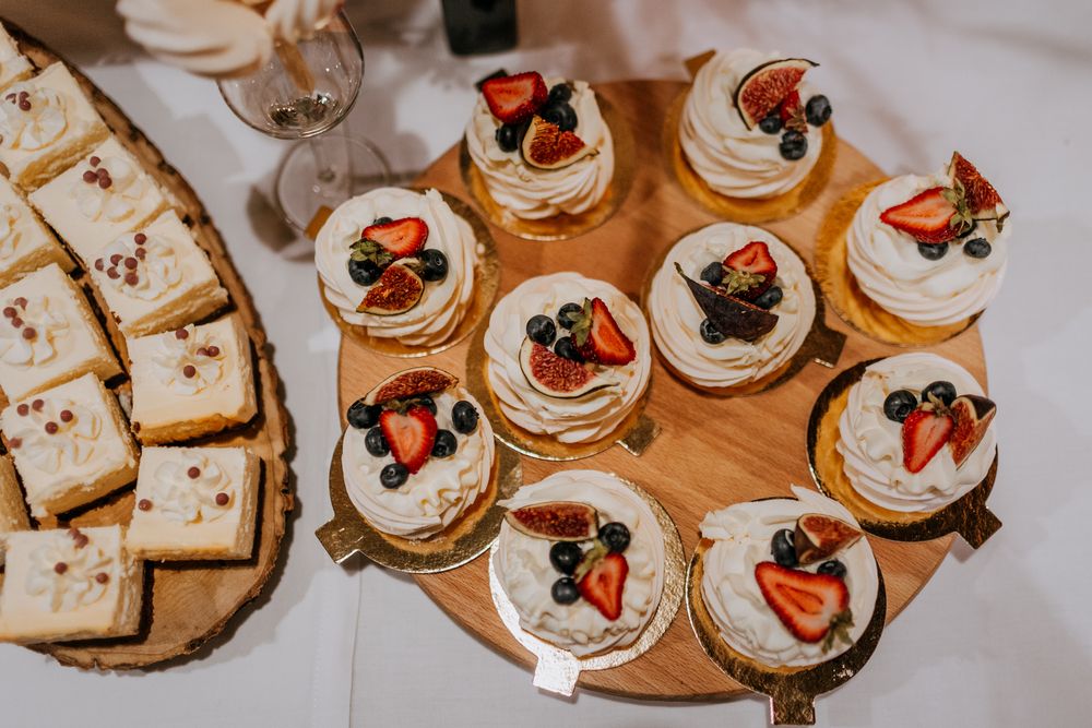 Wedding dessert display featuring cupcakes topped with fresh berries on a wooden serving board.