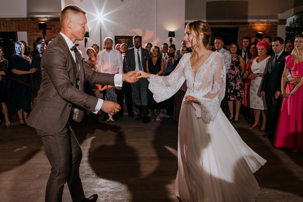 A couple dances energetically during their wedding reception while guests watch.