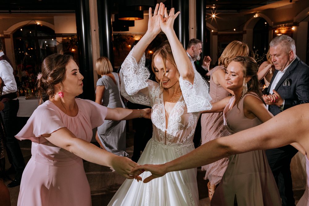 Wedding celebration on dance floor with guests in pink and neutral dresses dancing together.