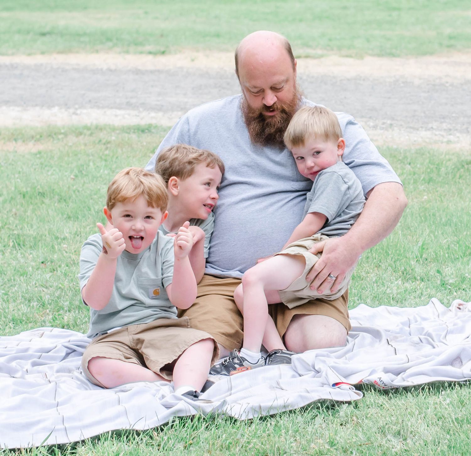 Sweet family bonding moments on a blanket in grassy outdoor setting.