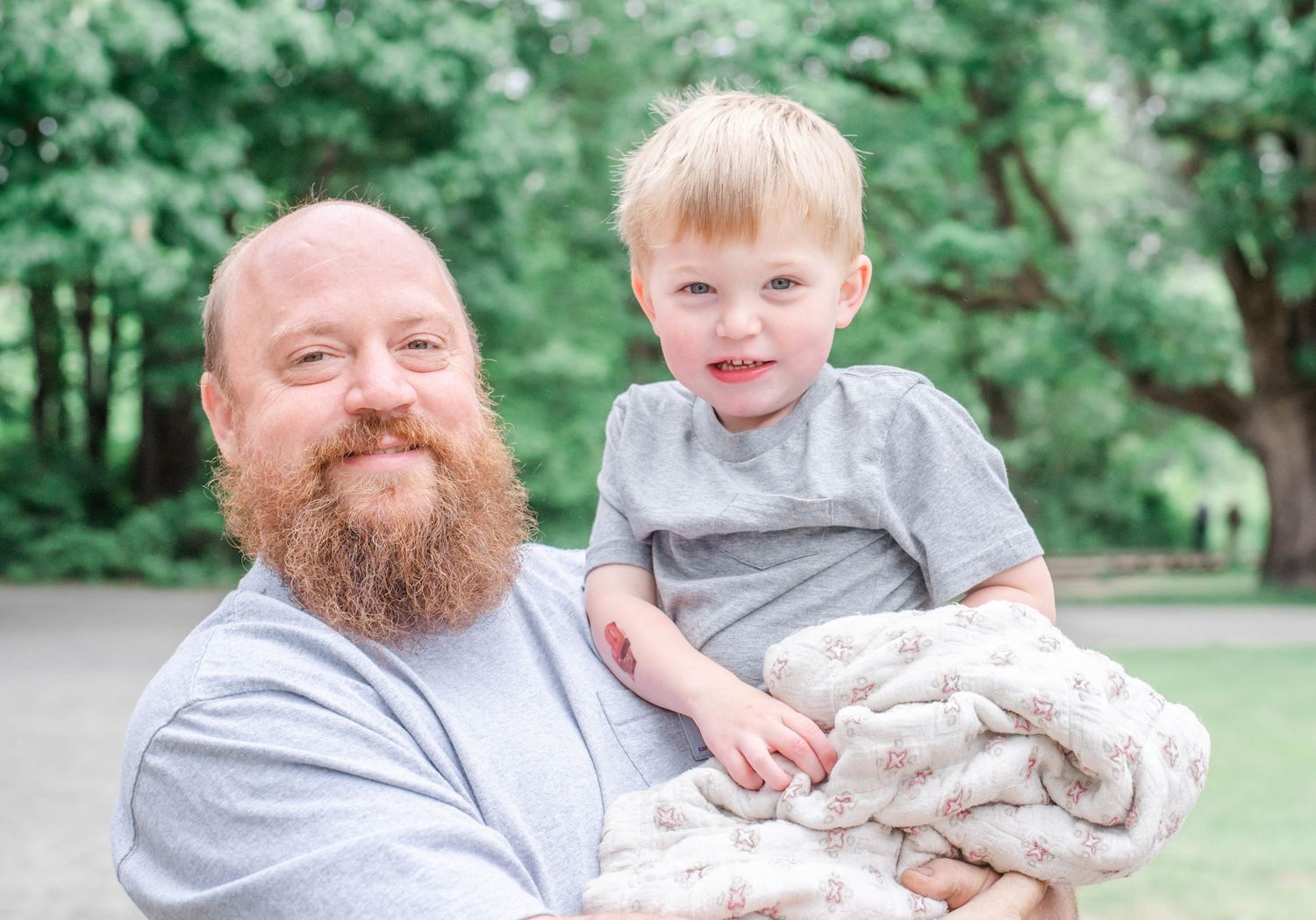 Family sharing tender moments together on grass with lush greenery background.