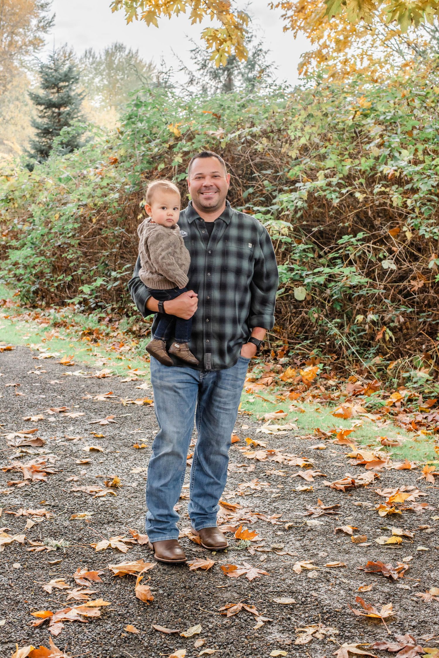 Fall scene with adult and child walking through fallen leaves on outdoor path.