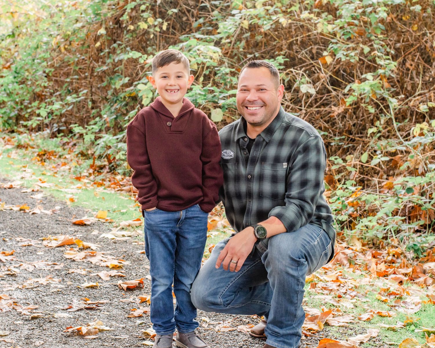A heartwarming autumn portrait of two people wearing coordinated casual outfits among fallen leaves.