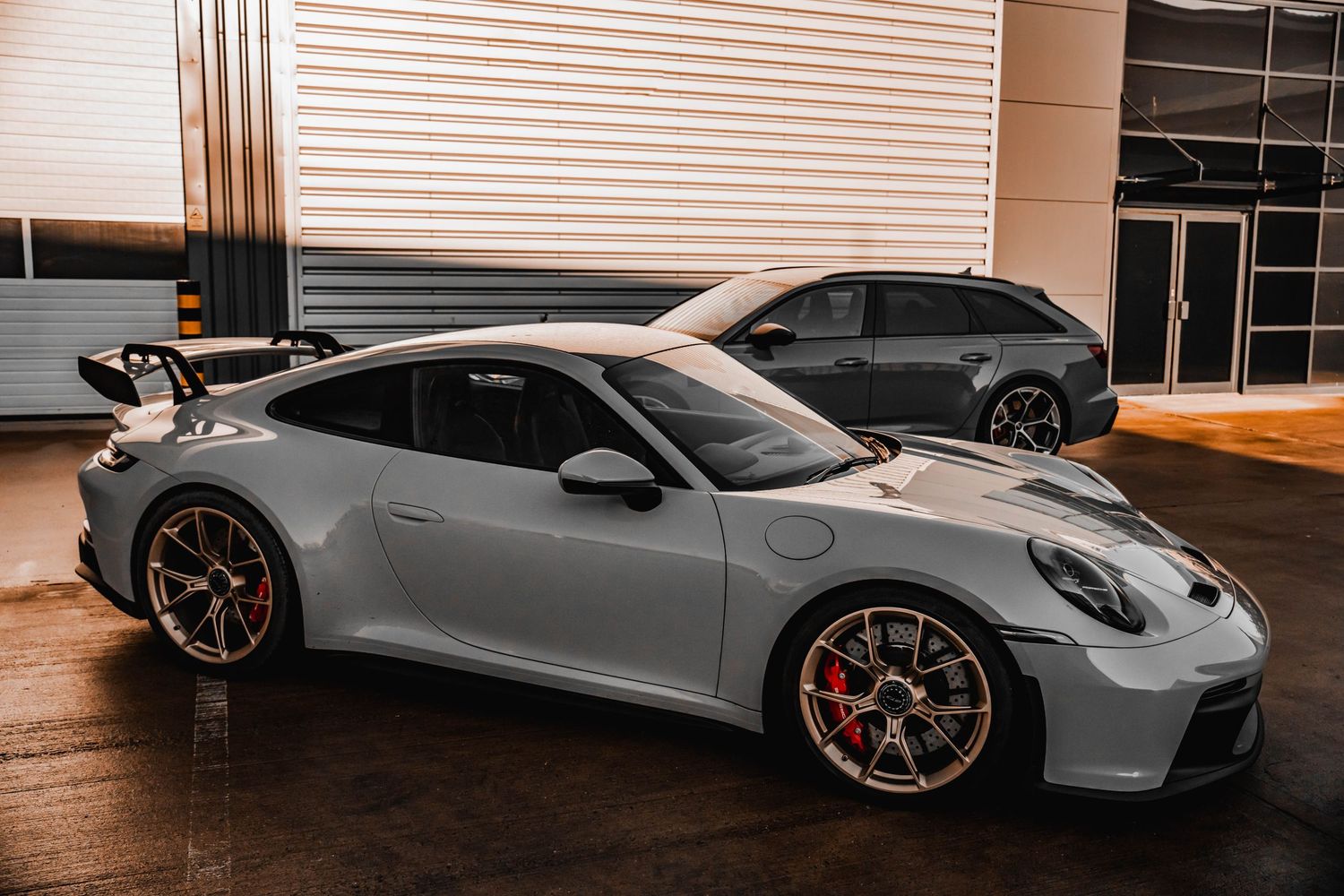 A sleek gray Porsche GT3 sports car sits on display in a showroom.