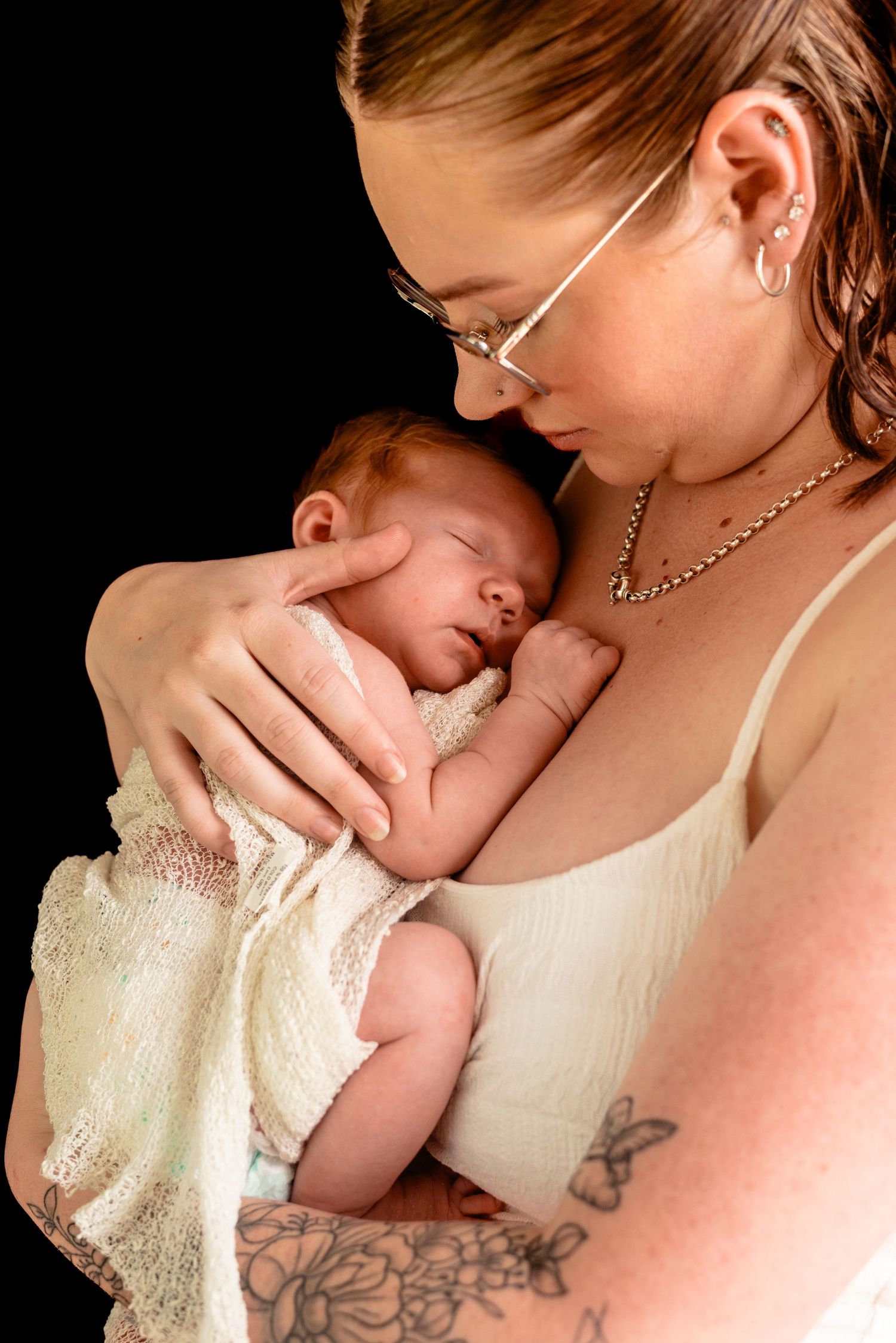 A tender moment between parent and newborn captured in dramatic lighting.