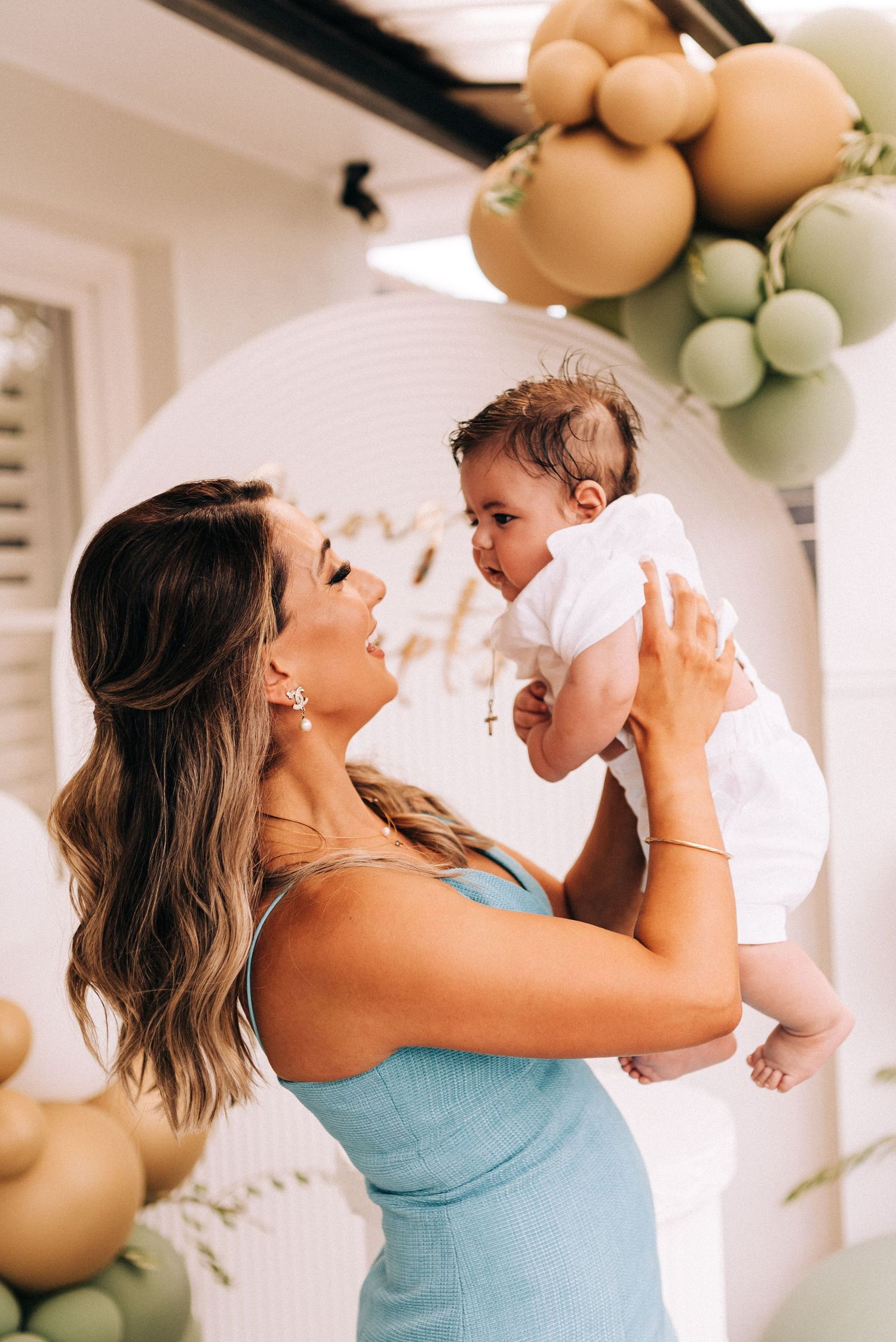 A joyful moment captured at a celebration with neutral colored balloon decor in the background.