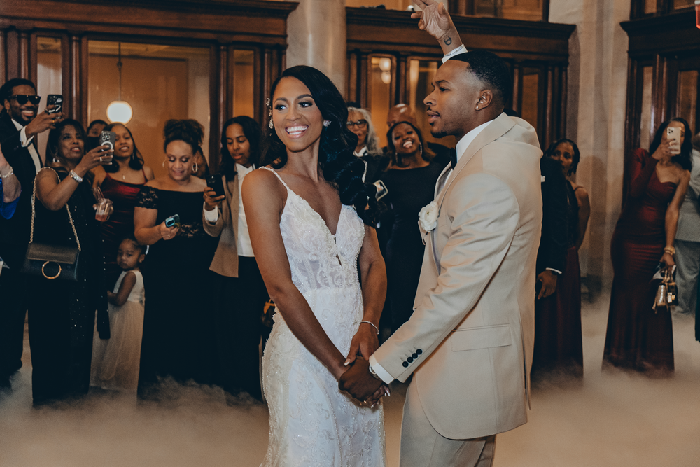 A beautiful moment at an elegant wedding reception as a couple holds hands in matching formal attire.
