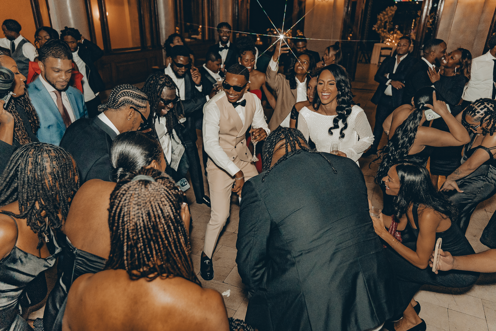 Lively dance floor scene at a wedding reception with guests dancing and mingling in formal attire.