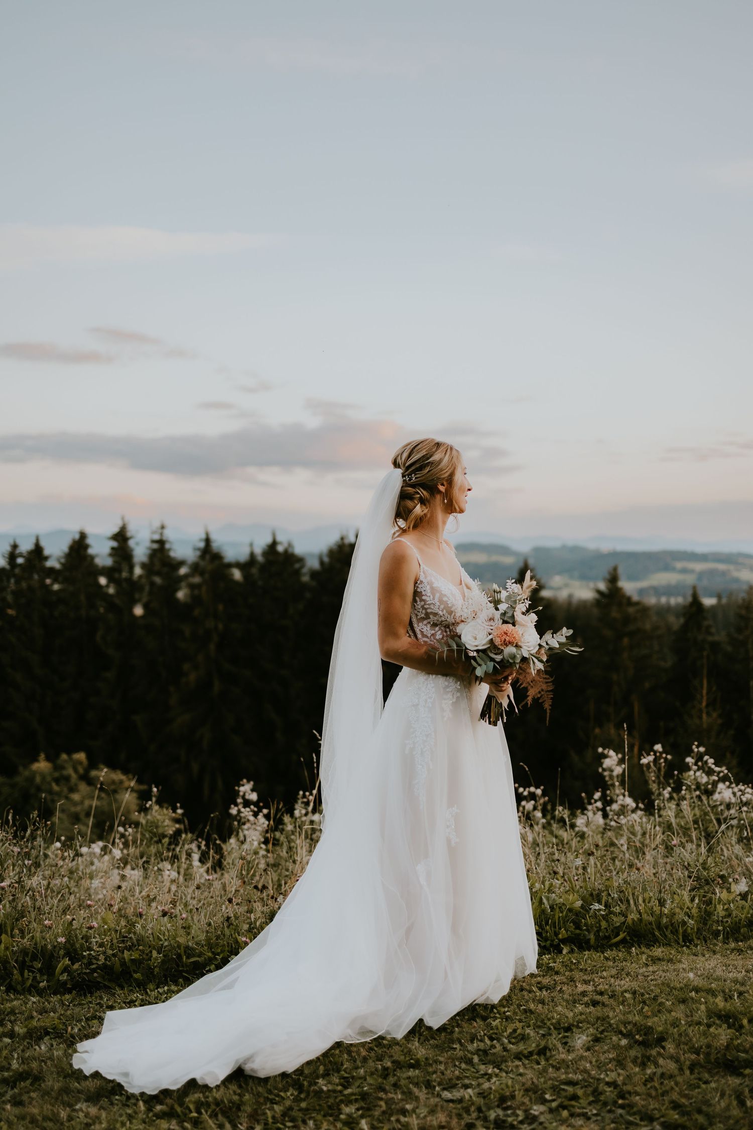 Braut blickt im Abendlicht über die Allgäuer Landschaft beim Berghotel Jägerhof in Isny – stimmungsvolle Silhouette im Sonnenuntergang