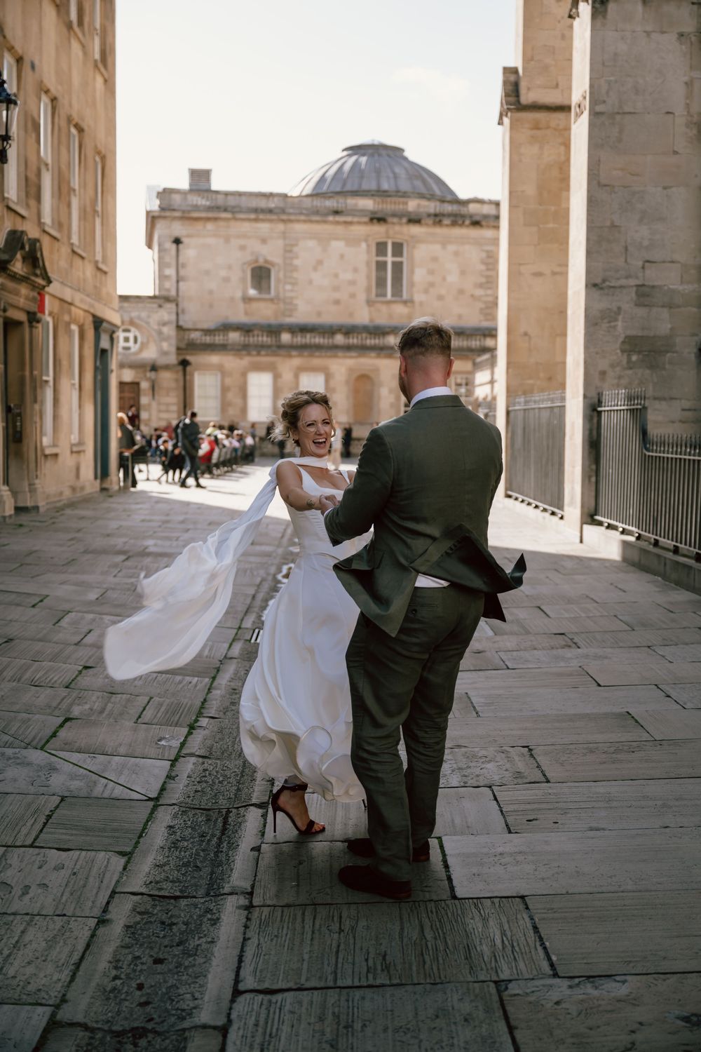 A newlywed couple celebrate in the streets of Bath, dancing infront of the Bath Abbey and Roman Baths