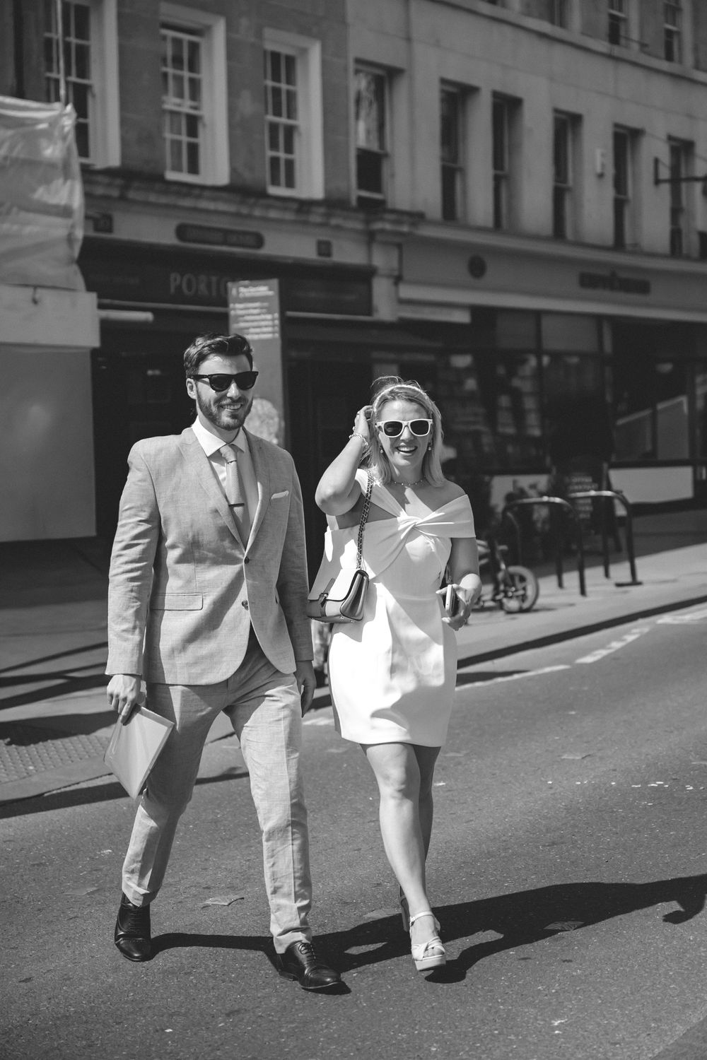 A stylish couple walking down a city street, to their wedding at the Guildhall in Bath in black and white photography.