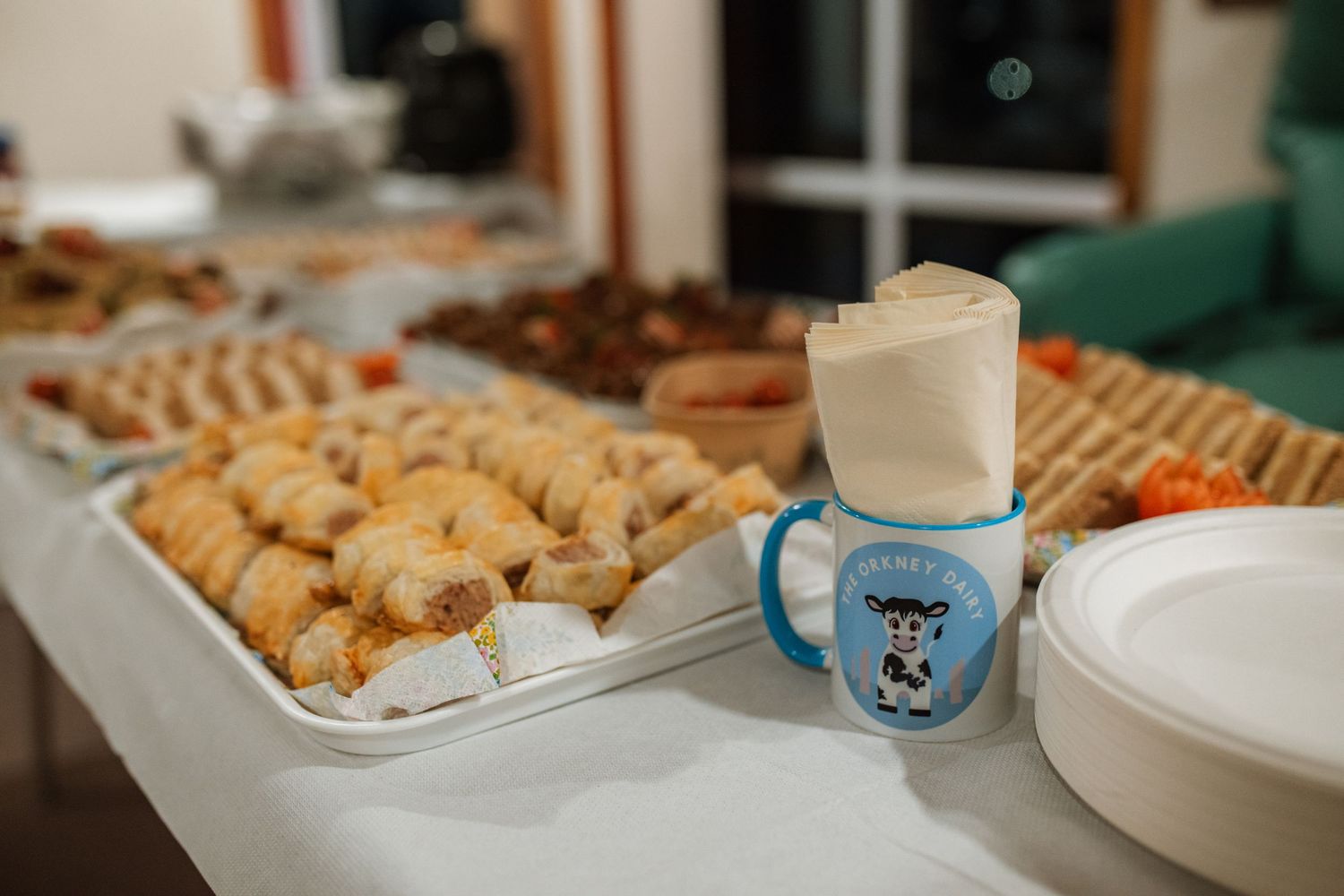 A variety of cookies and pastries displayed on a white platter next to a light blue sippy cup with cartoon design.