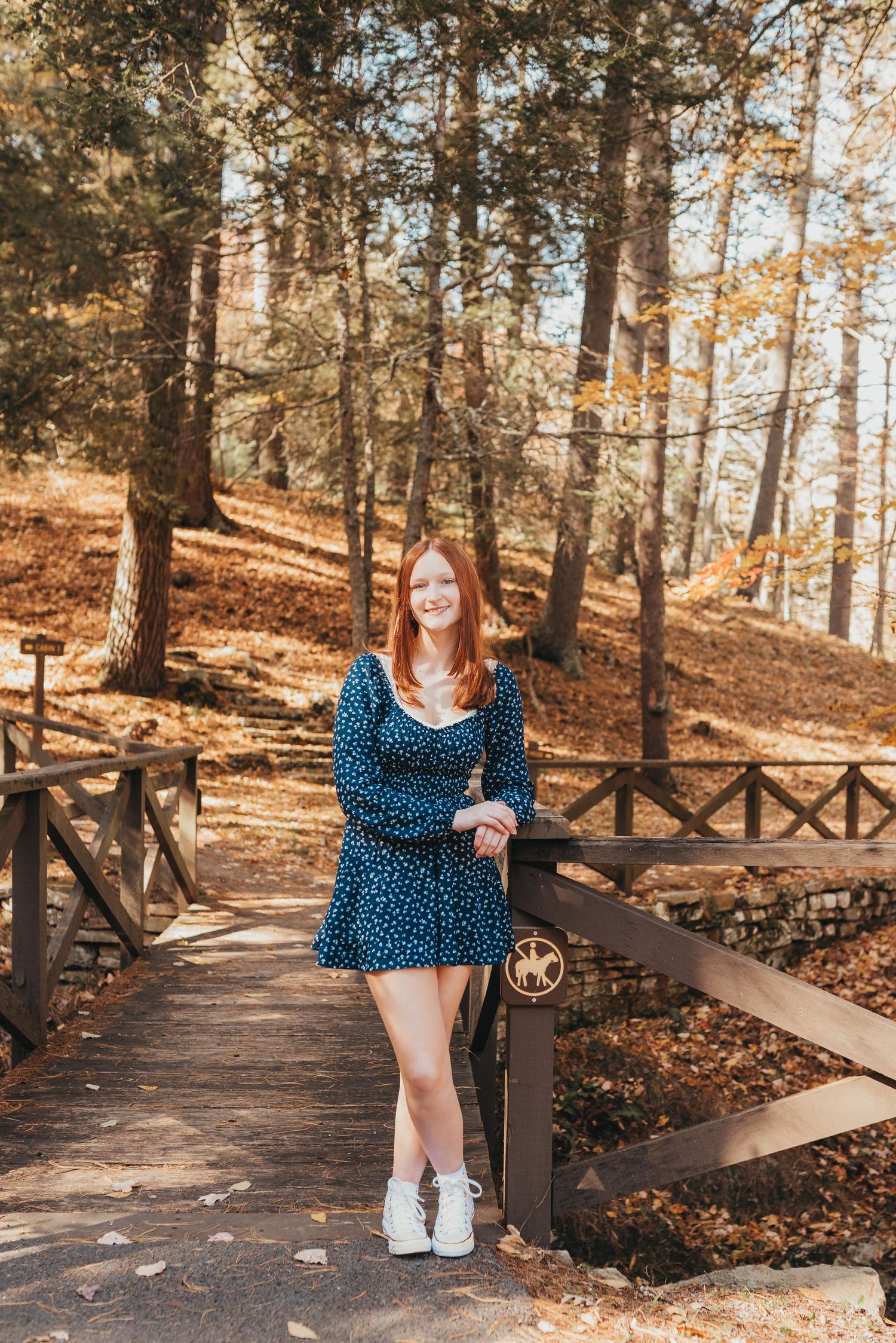 A portrait on a wooden boardwalk surrounded by fall forest scenery.