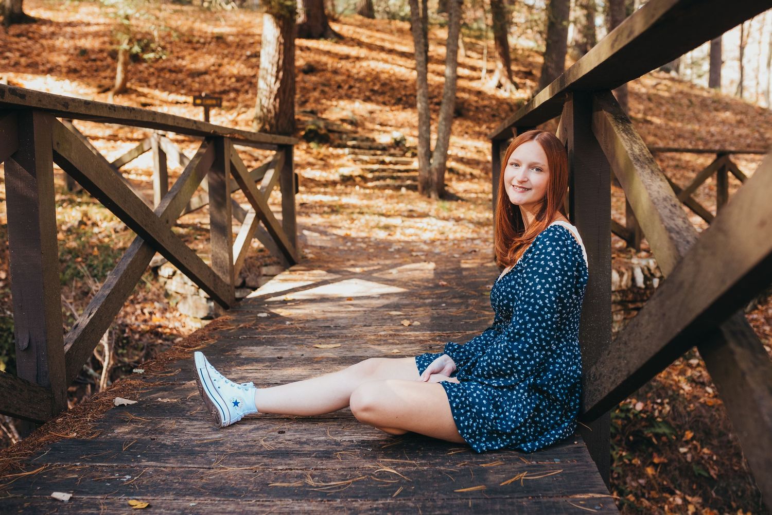A relaxed portrait sitting on wooden boardwalk steps in a forest setting.