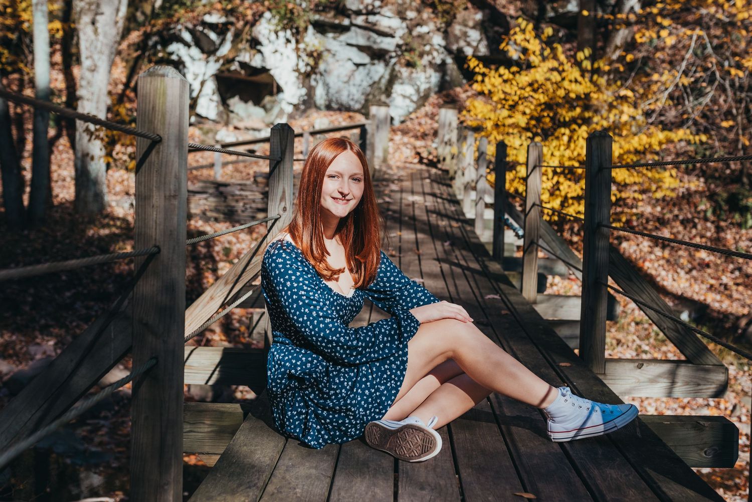 A casual autumn photoshoot on a wooden deck wearing a blue patterned dress.