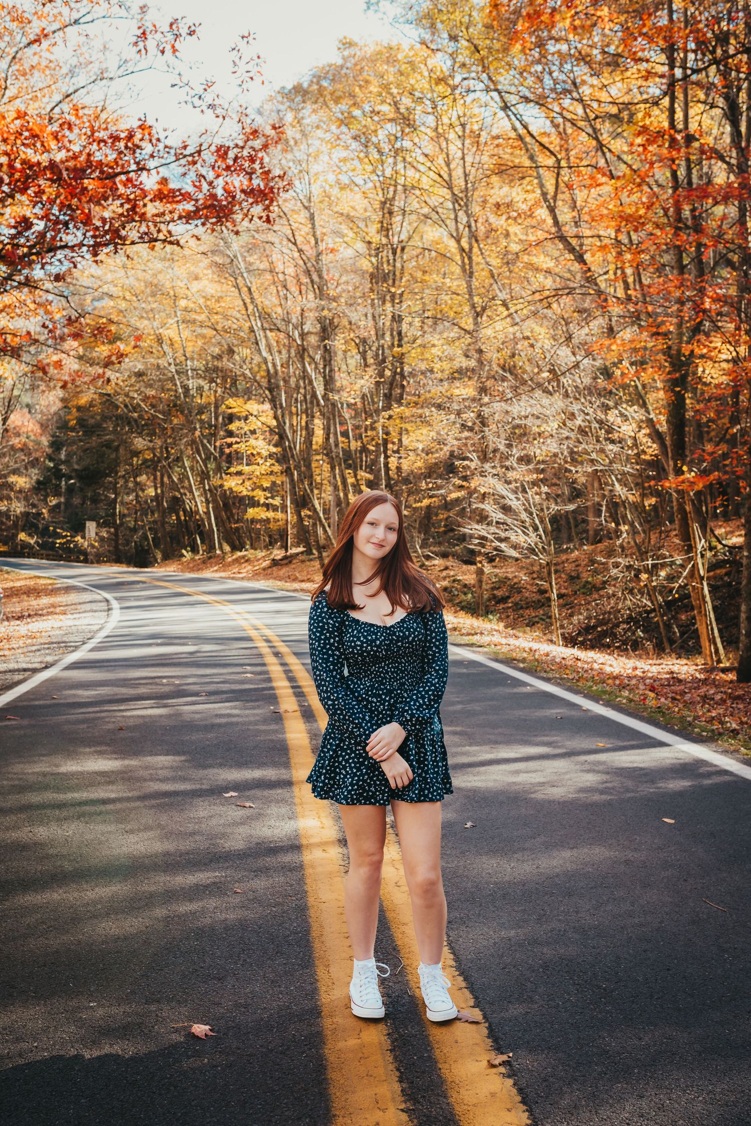 Standing on a road during fall with colorful autumn trees in the background.