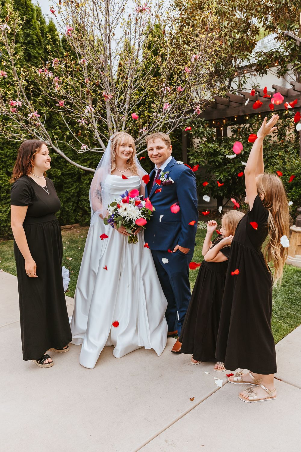 Wedding celebration with rose petals being tossed in a garden setting.