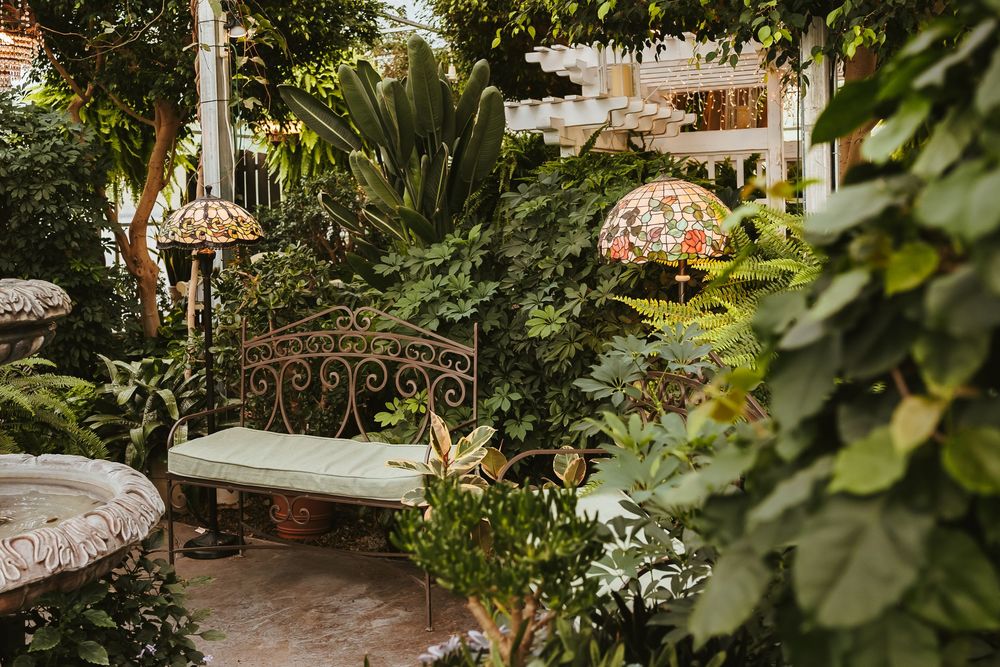 Ornate garden bench with decorative lighting and lush tropical plants.