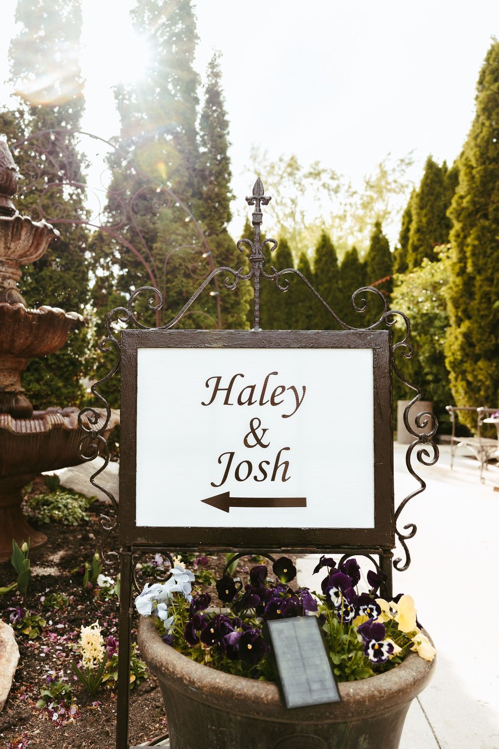 Elegant wedding sign in wrought iron frame displayed in garden setting.