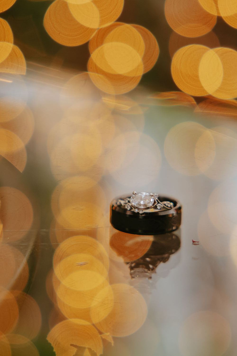 Wedding rings photographed with artistic bokeh lighting creating a romantic golden glow in the background.
