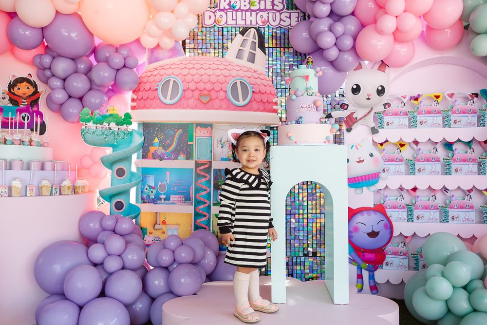 Birthday girl smiles in front of a vibrant Gaby’s Dollhouse party setup, captured by NYC family photographer Paula Brearley