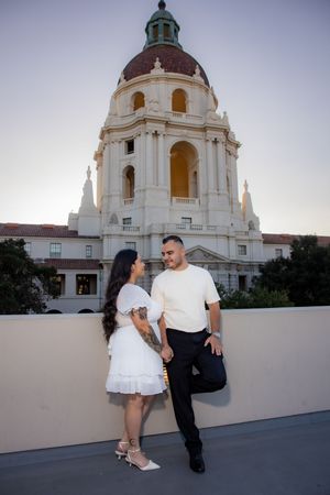 Couple holds hands in front of Pasadena City Hall at sunset during engagement photo session.