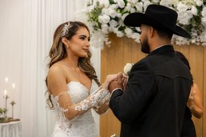 Bride and groom exchanging rings at wedding ceremony altar adorned with white floral arrangements and candles.