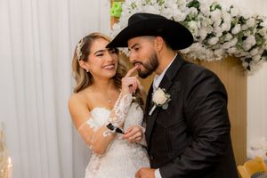 Bride and groom sharing a playful moment together near white floral arrangements at their wedding reception.