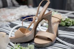 Elegant nude platform wedding heels with rhinestone embellished block heels on a striped surface.