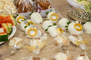 White chocolate wedding favor candies with gold ring decorations displayed on wooden table.