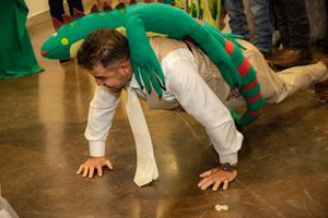 Wedding guest performing fun push-up dance move wearing green dragon costume at reception.