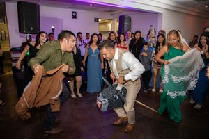 Wedding guests enjoying lively dance floor celebration with colorful costumes at reception.