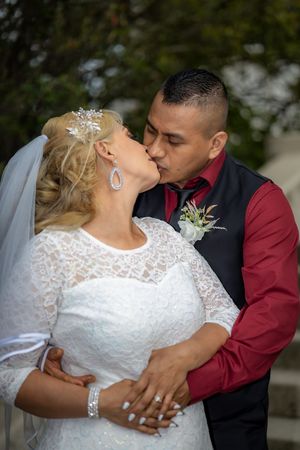 Bride and groom share a romantic kiss during their outdoor wedding portrait session.