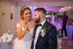 Smiling bride and groom in elegant wedding attire share a joyful moment at their reception.