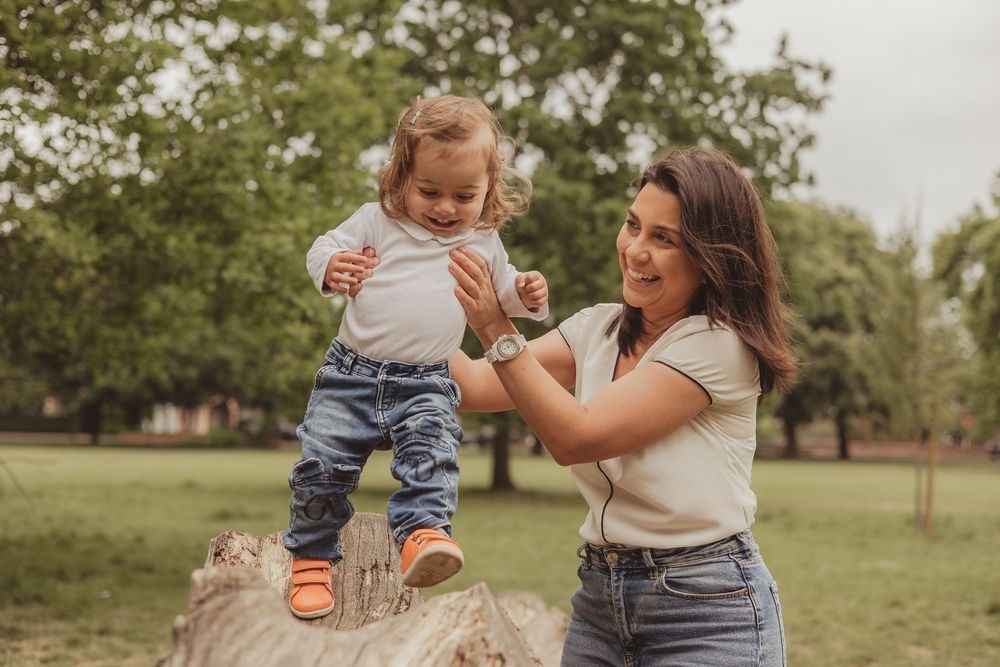 mum helping toddler to walk across a log