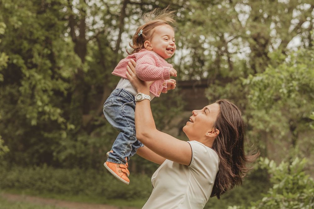 mum throws toddler in the air laughing