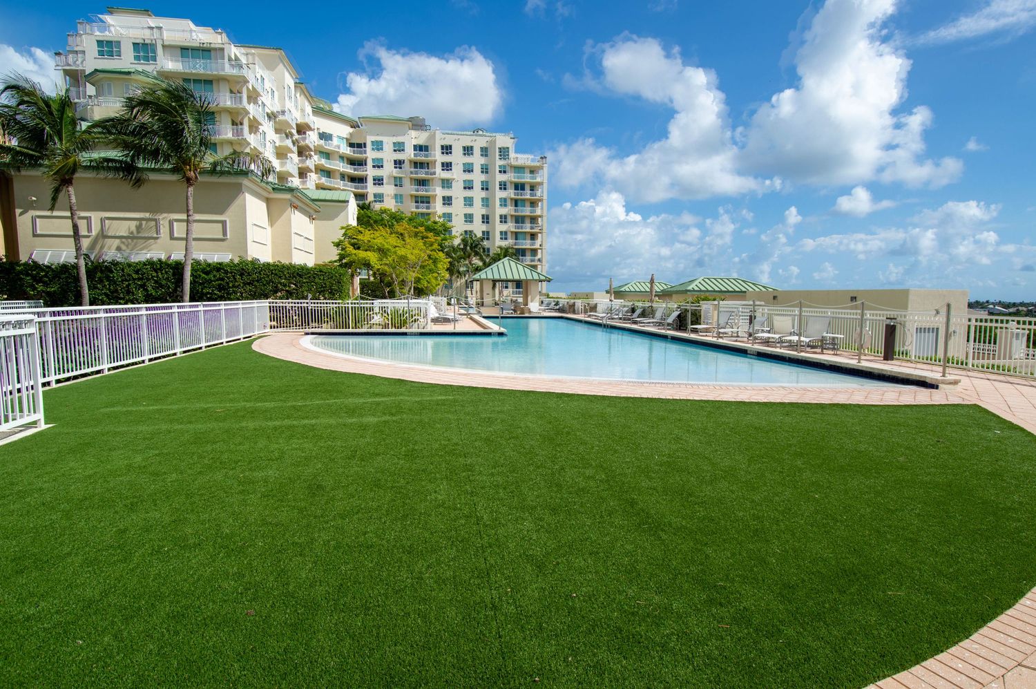 Luxury beachfront condominium complex with swimming pool and artificial turf deck.