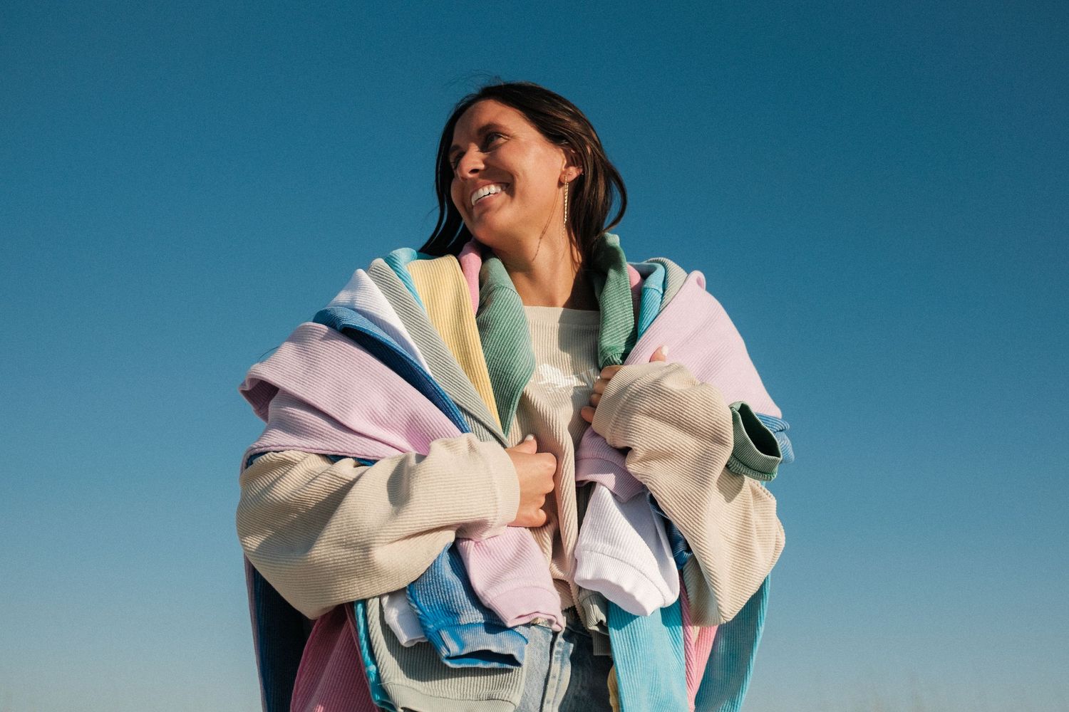 People wearing pastel colored clothing against a bright blue sky background.
