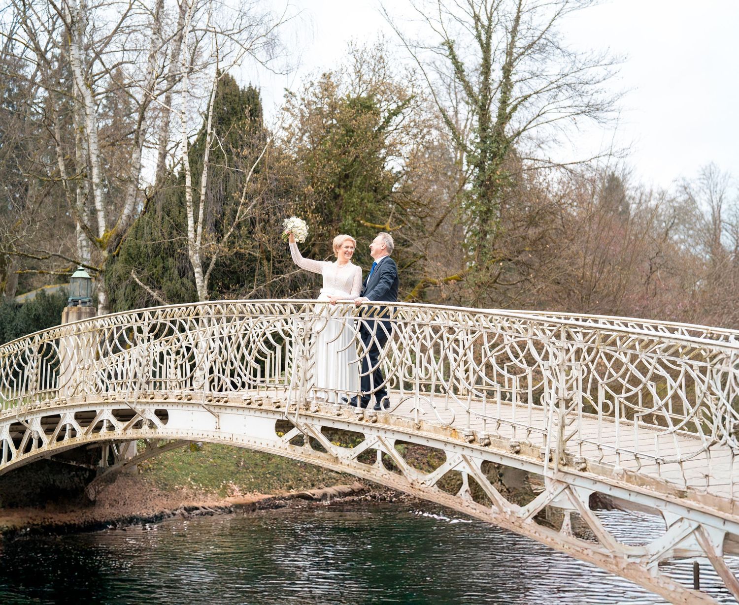 Hochzeitspaar auf einer Fußgängerbrücke mitten in Rastatt, umgeben von urbaner Kulisse und natürlichem Licht.