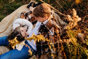 A couple shares a romantic moment together in a golden sunlit field during sunset.