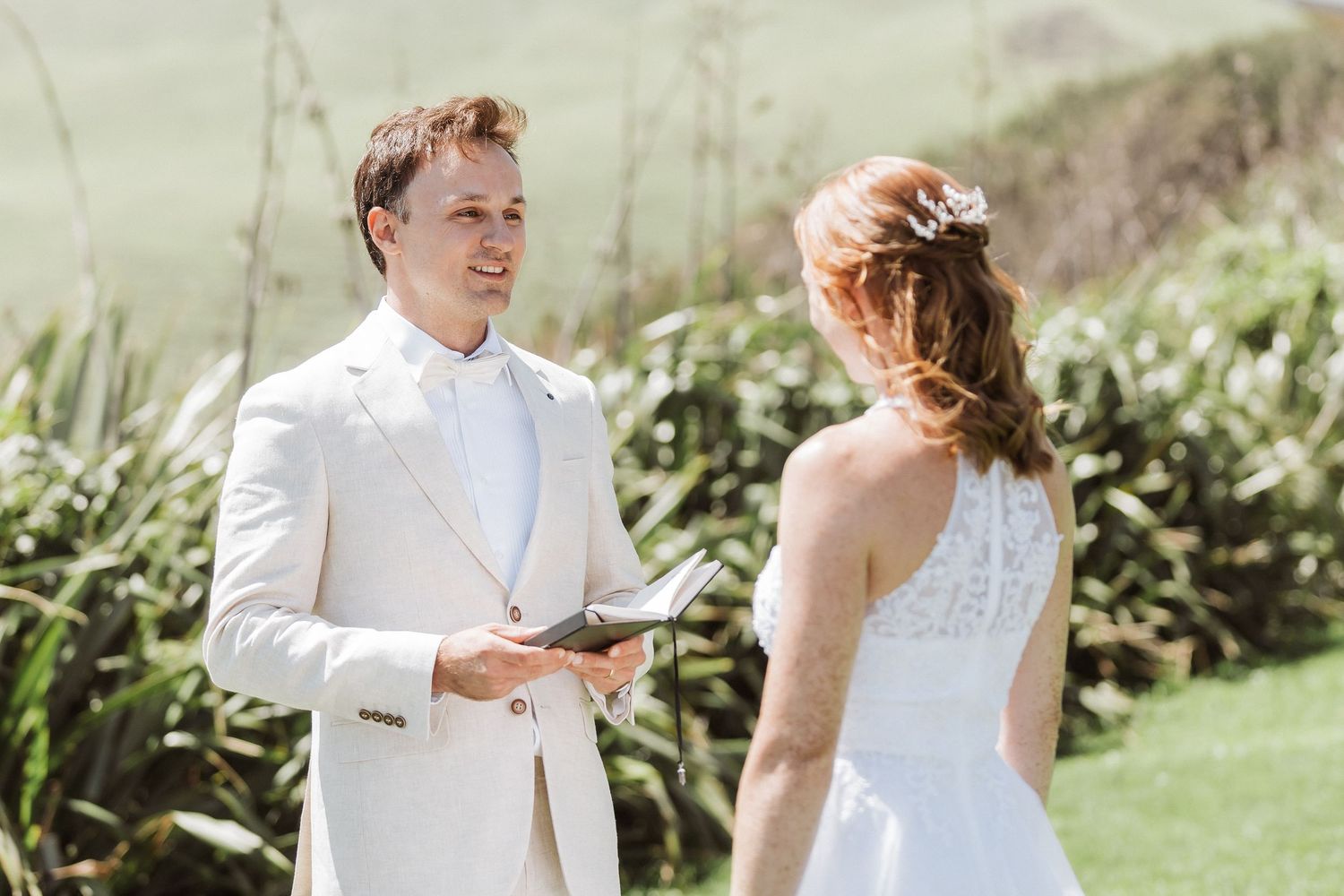 White horse in golden mountain meadow during sunset with mountains in background.