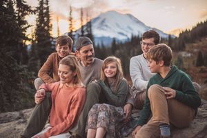 Family hiking and traveling to Mt. Rainier and sitting together during a family photoshoot in Mt. Rainier National Park in Washington