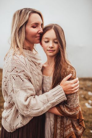 Mom and daughter standing together at a mountains edge in the Dolomites Italy during their family adventure photoshoot