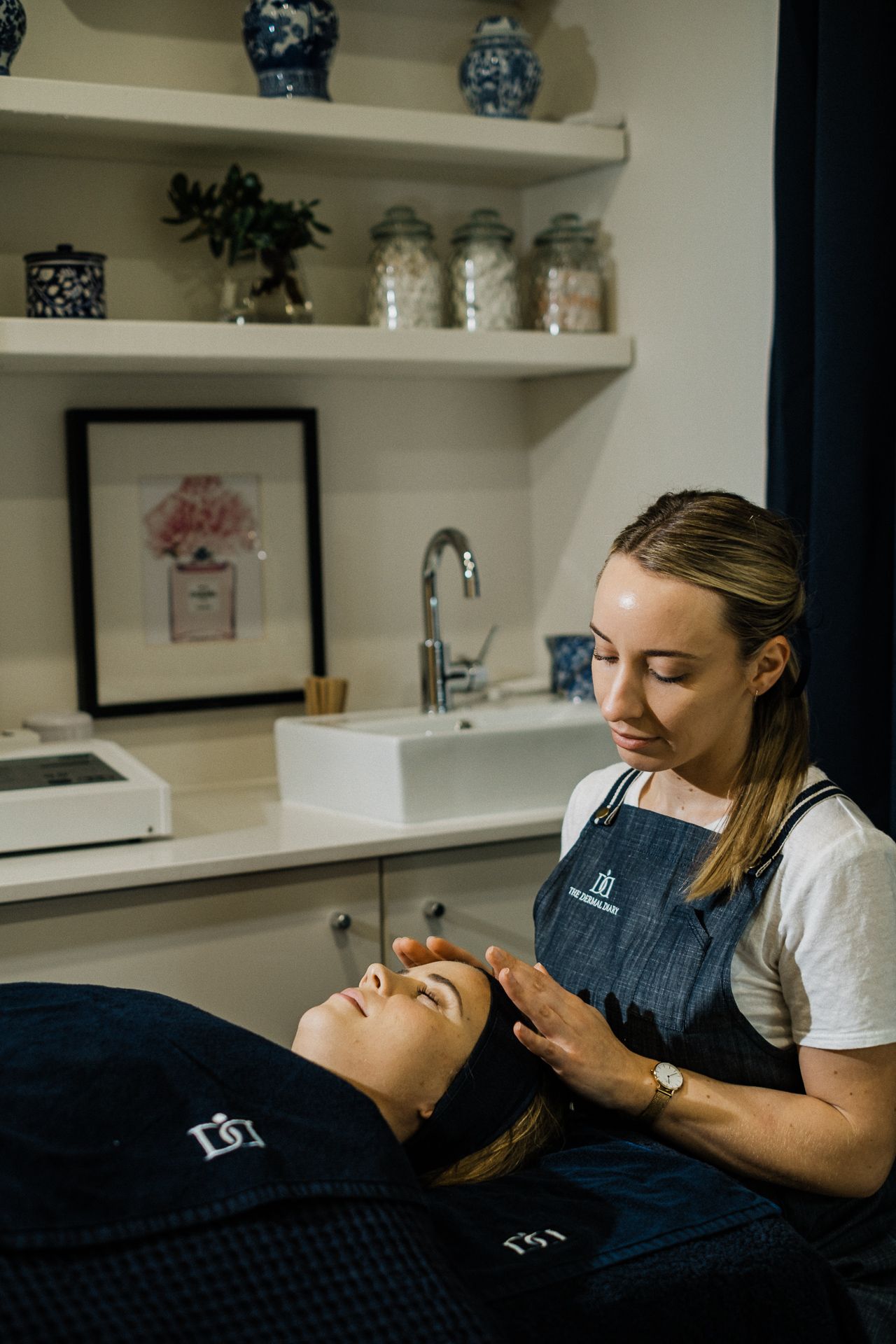 A therapeutic massage session takes place in a serene treatment room with white shelves and decor.